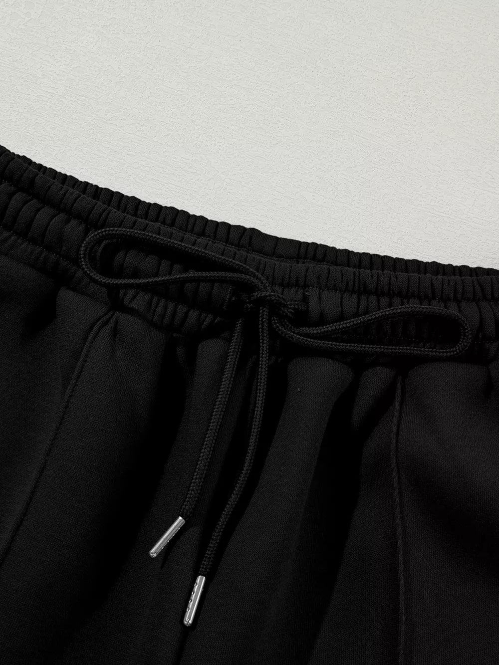 Black cotton joggers with drawstring waist and silver-tipped cords.