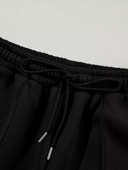 Black cotton joggers with drawstring waist and silver-tipped cords.