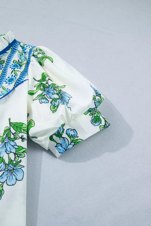 White polyester shirt with blue floral print, puff sleeves, and ruffled neckline detail.