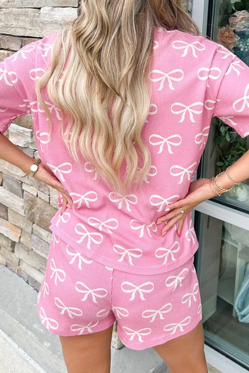 Pink ribbed loungewear set with white bow print, short sleeves and shorts.