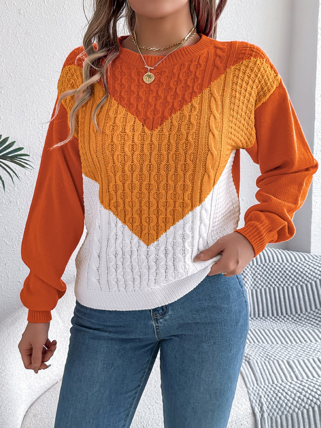 Chevron cable knit sweater in orange, yellow, and white with a contrast color block design.