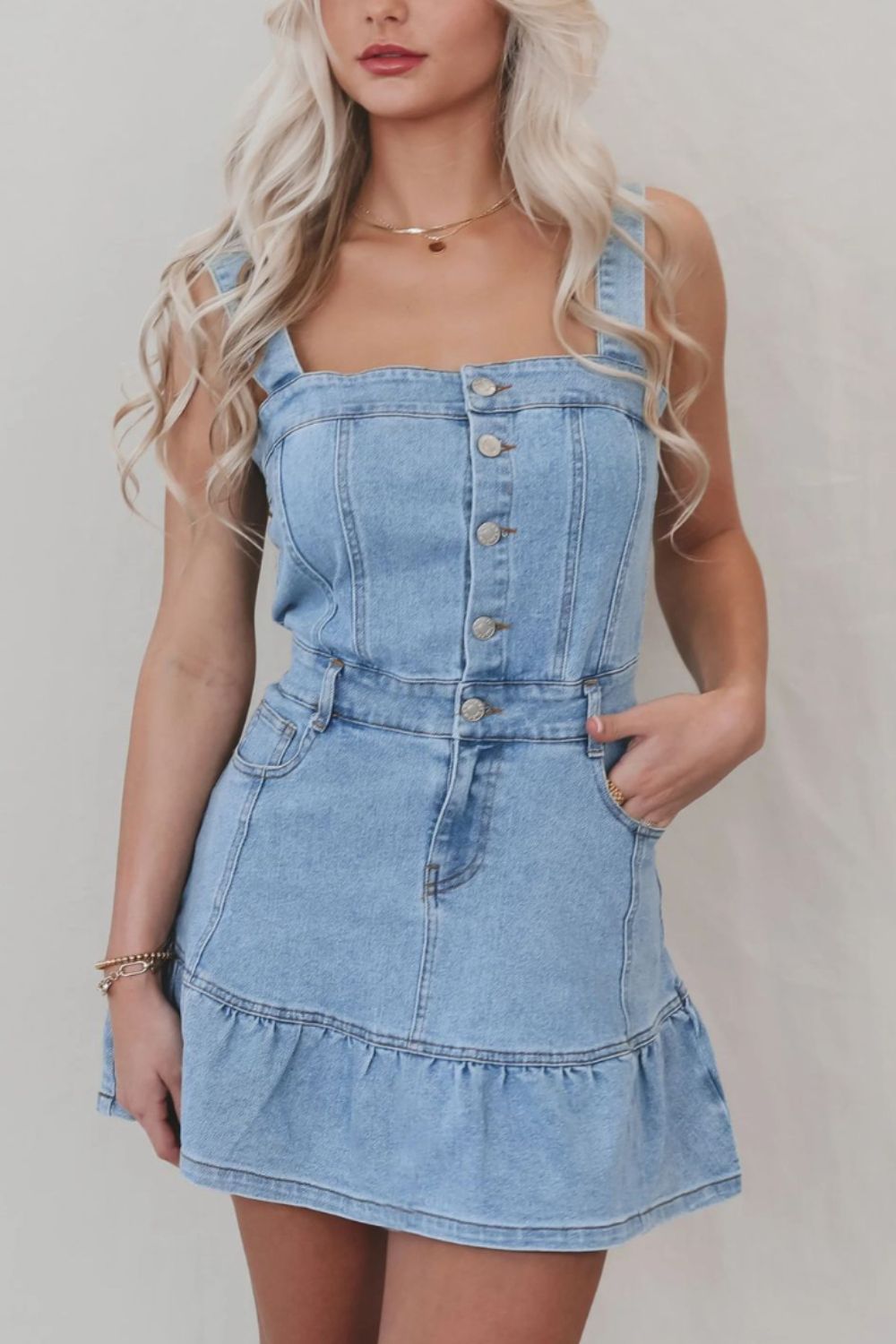 Button-front denim sundress with square neckline, ruffle hem, and adjustable straps.