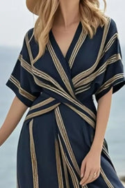 Dark navy wrap maxi dress with gold stripes, V-neck, short sleeves, and a flowing skirt.