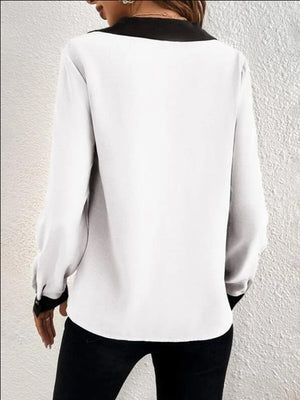 White blouse with black contrast collar and cuffs, V-neck, long sleeves.