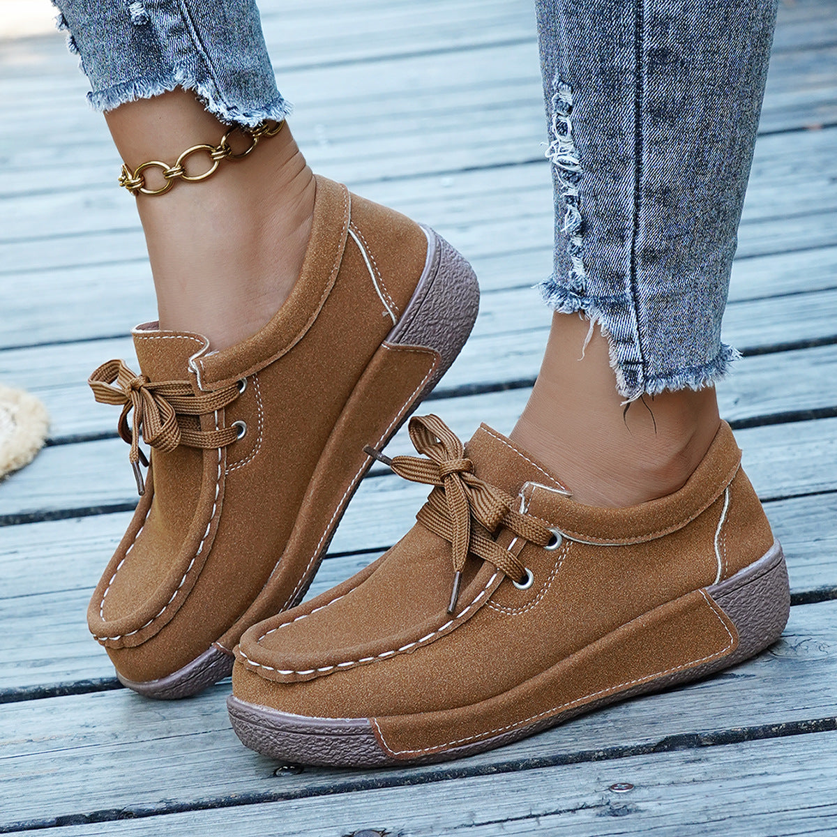 Brown suede lace-up moccasin style sneakers with white stitching detail.