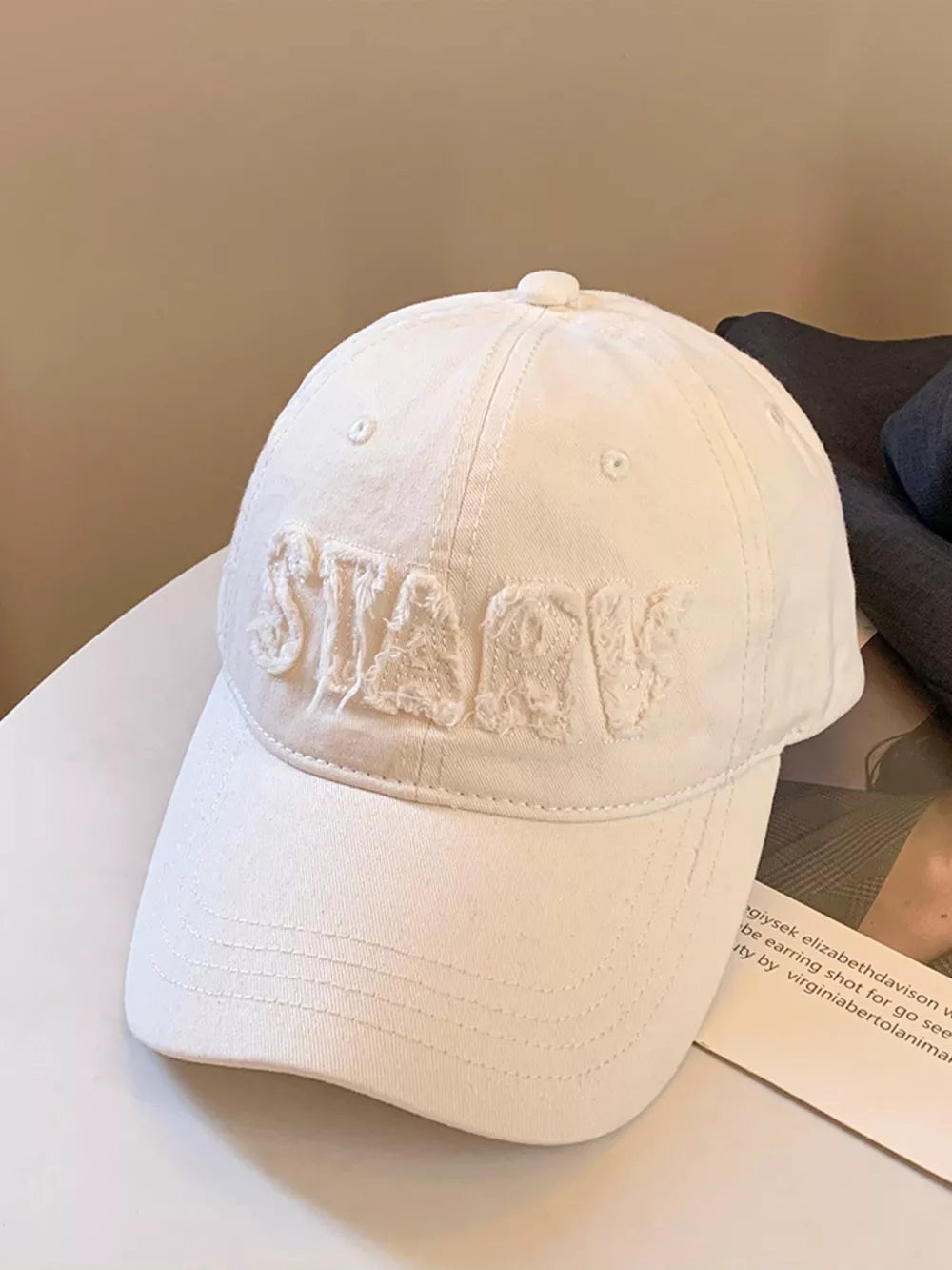 Milky white cotton baseball cap with distressed applique letters and a curved brim.