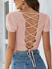 Blush pink crochet crop top with short sleeves and a lace-up back detail.