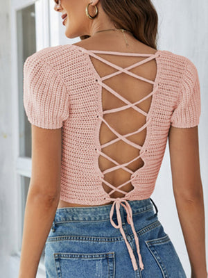 Blush pink crochet crop top with short sleeves and a lace-up back detail.