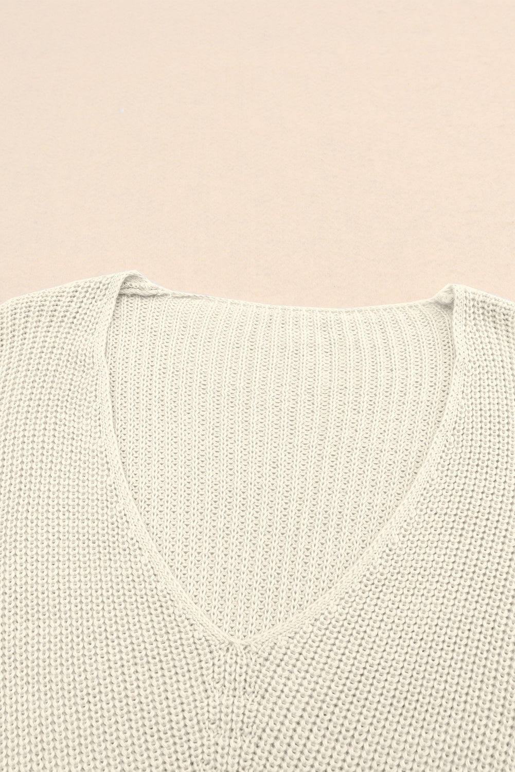 Relaxed knit V-neck pullover sweater in beige acrylic with ribbed texture.