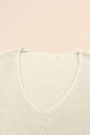 Relaxed knit V-neck pullover sweater in beige acrylic with ribbed texture.