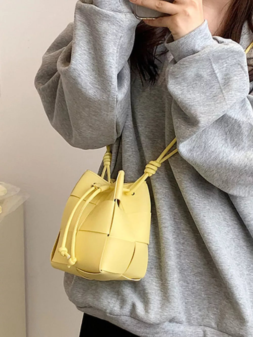 Yellow woven mini bucket bag with drawstring closure and tie straps.