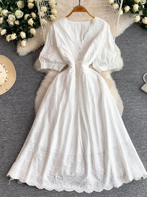 White lace-embellished A-line midi dress with V-neck, short puff sleeves, and button front.