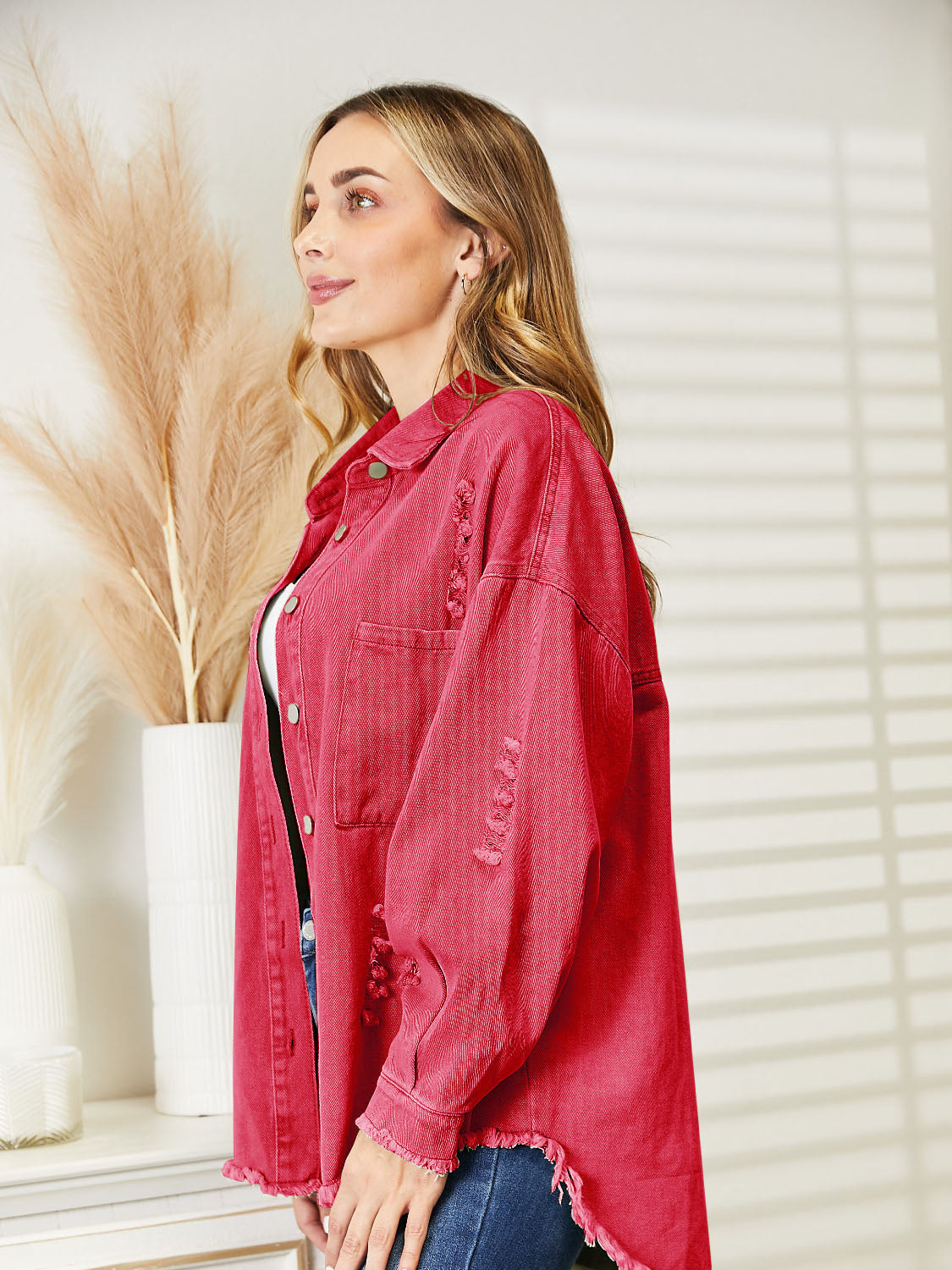 Distressed denim overshirt in orange-red with raw hem and buttoned front.