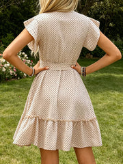 Apricot polka dot dress with ruffle sleeves, tie waist, and tiered hem.