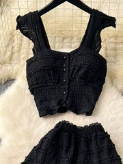 Black textured two-piece set with ruffled details, buttoned crop top and ruffled skirt.
