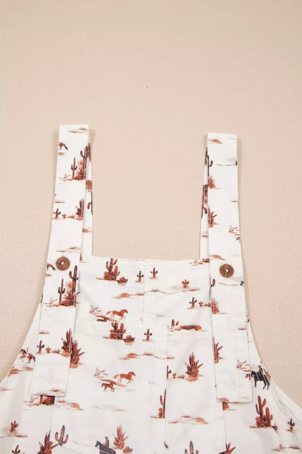 Desert motif adjustable jumpsuit in white with cactus and horse print, cotton fabric.