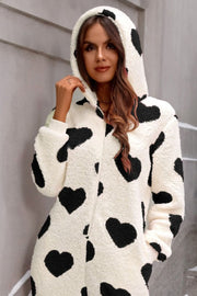 White sherpa onesie with black hearts and hood, long sleeves, casual loungewear.