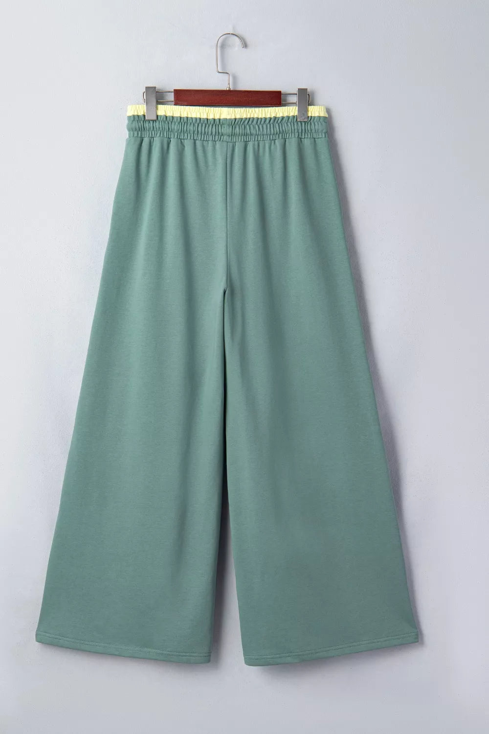Green cotton sweatpants with wide legs and a yellow drawstring waistband.