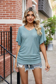 Teal perforated dolman sleeve blouse with V-neck and ruching detail.