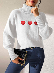 White knit turtleneck sweater with red heart appliqués and balloon sleeves.