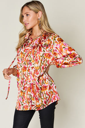 Silk ikat tie-neck blouse with button closure and abstract print in tangerine, pink, and green.