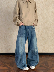 Men's blue washed wide-leg jeans with paneling and a silver chain detail.