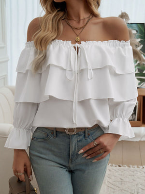 White tiered ruffle off-shoulder blouse with tie neck and ruffled cuffs.