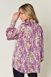 High neck abstract print blouse in red-violet with smocked cuffs and collar.