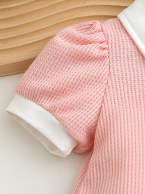 Pink waffle knit baby dress with puff sleeves, white collar and cuffs.