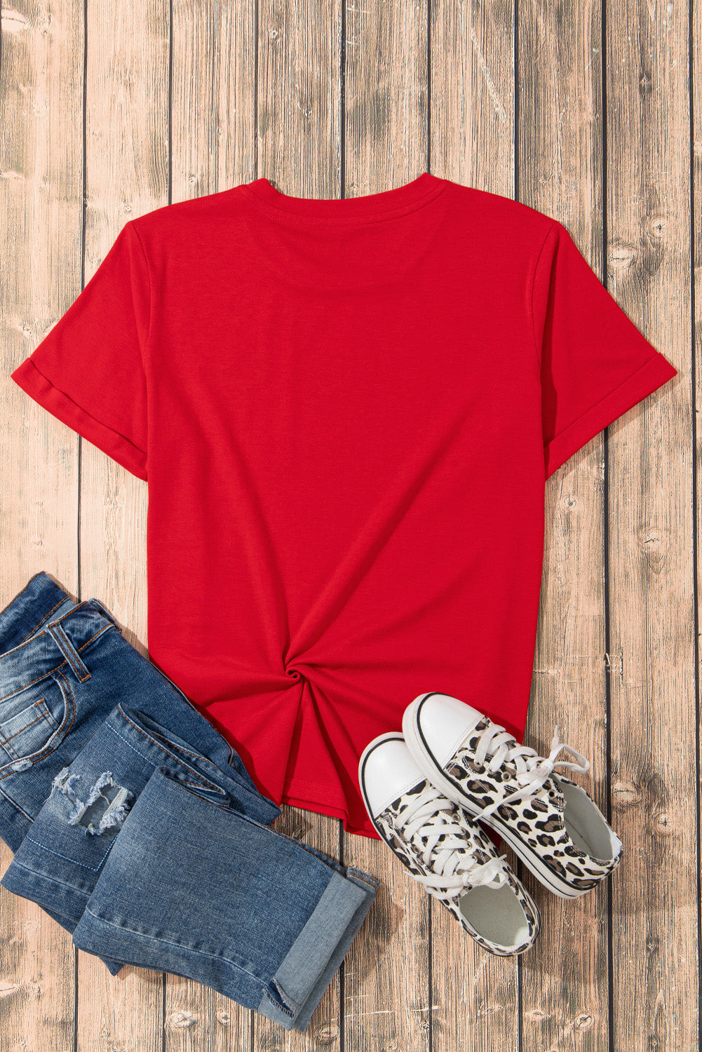 Red crew neck t-shirt with knotted hem detail, styled with jeans and leopard print sneakers.