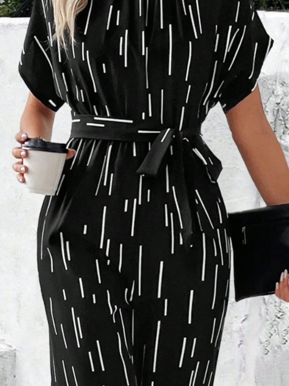 Black wide-leg jumpsuit with raindrop print, short sleeves, and a tie waist.