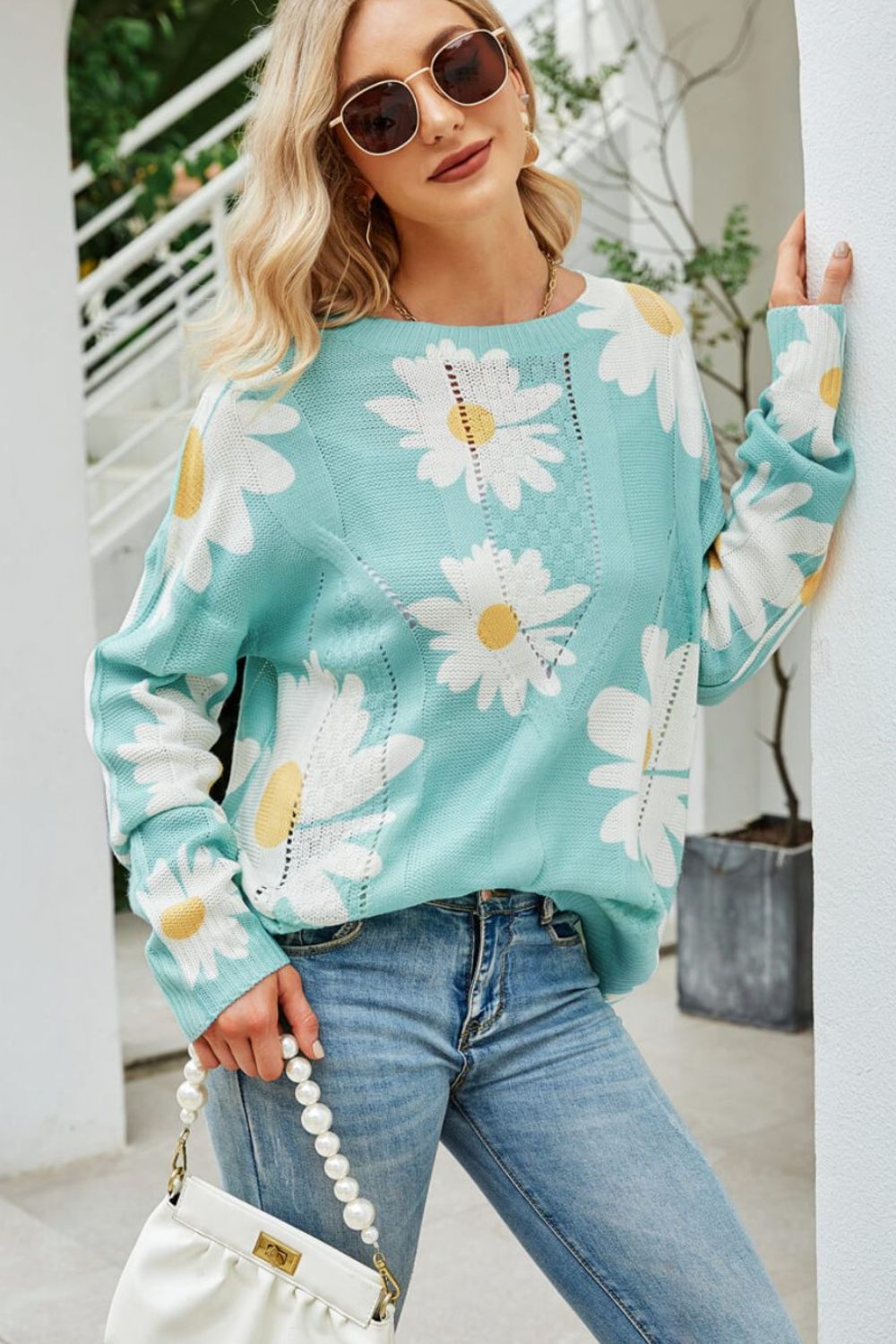 Green intarsia knit sweater with large white daisy pattern and open knit details.