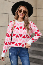Pink and red heart pattern knit sweater with crew neck and long sleeves.