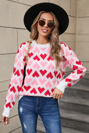 Pink and red heart pattern knit sweater with crew neck and long sleeves.