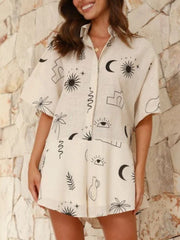 Beige linen romper with celestial print, button front, short sleeves, and flared hem.