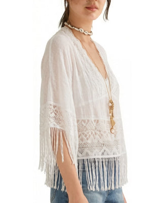 White bohemian lace cover-up with fringe and V-neck, styled with jeans.