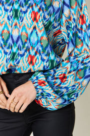 Prismatic ikat blouse with voluminous sleeves in blue and green, featuring a vibrant abstract pattern.