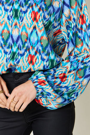 Prismatic ikat blouse with voluminous sleeves in blue and green, featuring a vibrant abstract pattern.