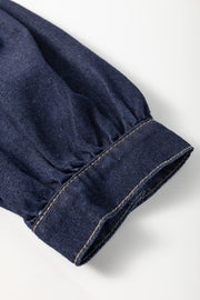 Denim puff sleeve detail on a dark mini dress with visible stitching.