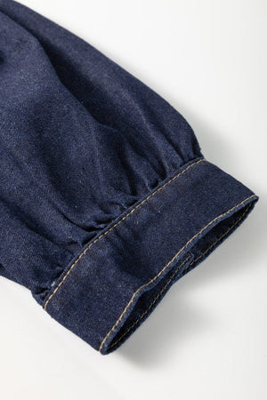 Denim puff sleeve detail on a dark mini dress with visible stitching.