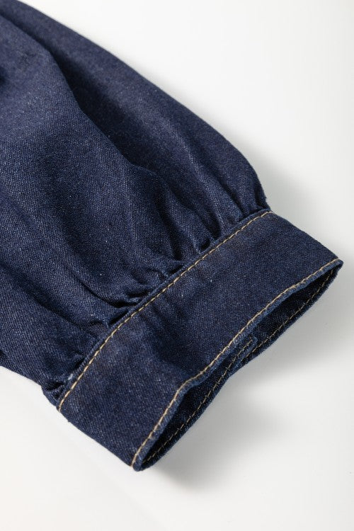 Denim puff sleeve detail on a dark mini dress with visible stitching.