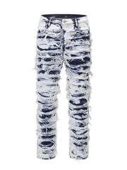 Distressed shredded denim jeans in medium wash with artistic sculptural details.