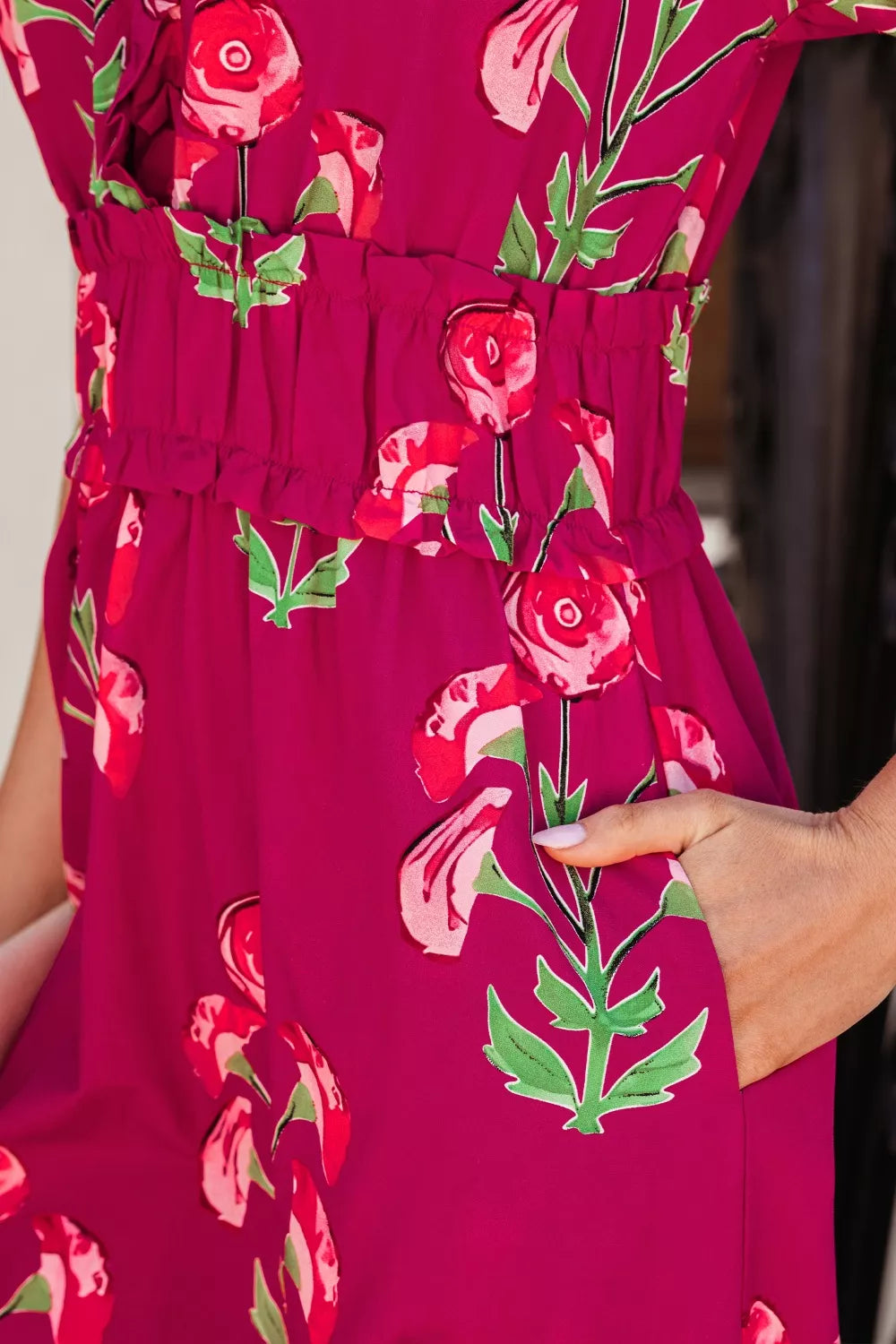 Charming floral tiered midi dress in magenta with red roses and green leaves, featuring a ruffled waist and pockets.