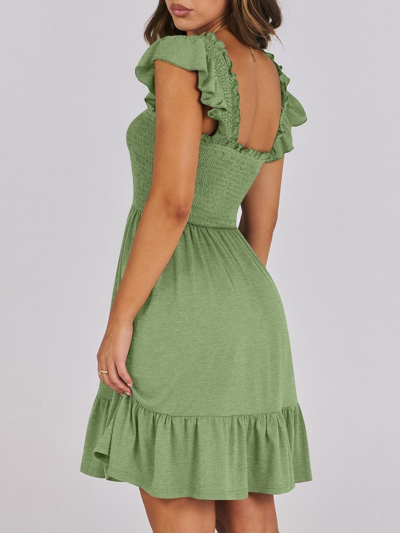 Sage green smocked mini dress with ruffle trim and flutter sleeves.