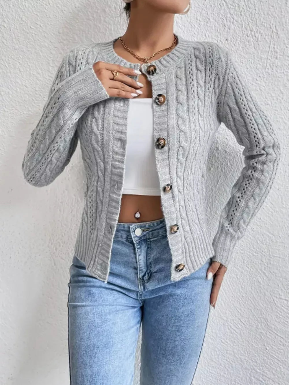Gray cable-knit button-front cardigan with round neckline and tortoise buttons.