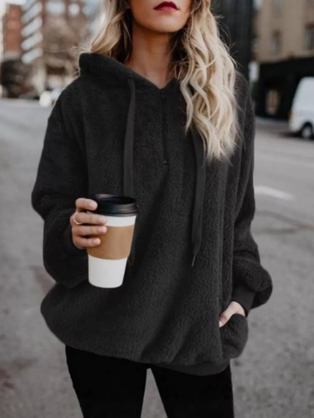 Black cozy fleece hoodie with drawstring and pockets, worn by a woman holding a coffee cup.