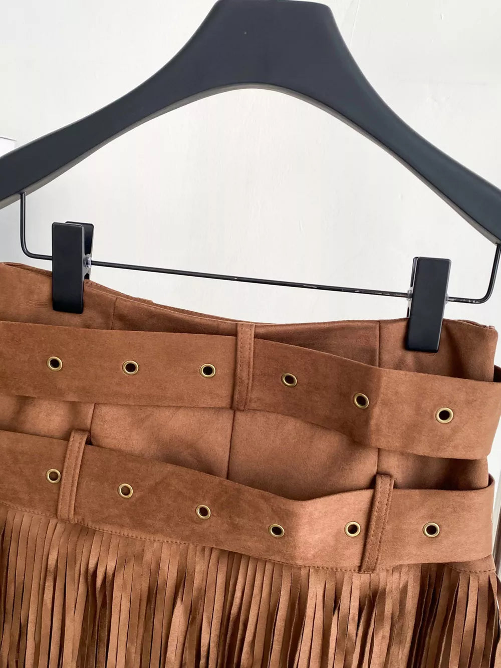 Belted mini skirt in brown suede with fringe and antique brass grommets.