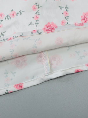 White midi dress with pink floral print and spaghetti straps, showing hem detail.