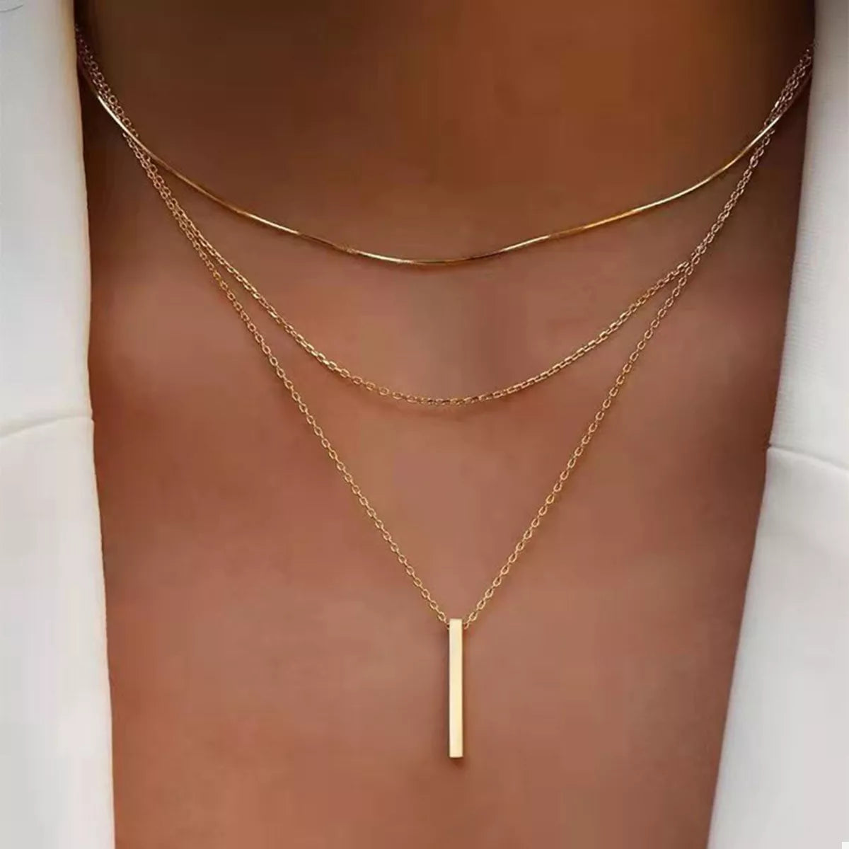 Gold layered bar pendant necklace with delicate chains.