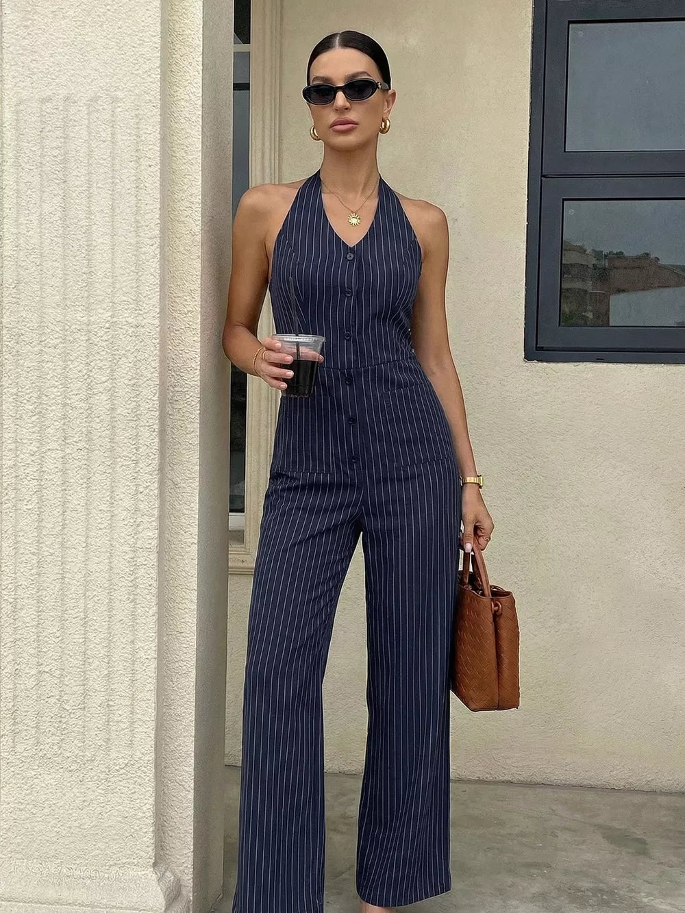 Chic navy pinstripe halter jumpsuit with decorative buttons and wide legs.